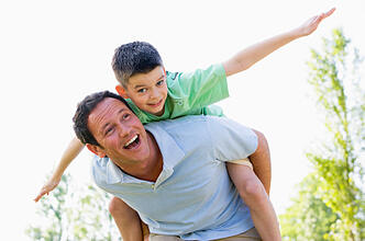 Man giving young boy piggyback ride outdoors